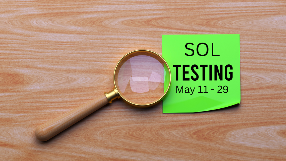 Magnifying glass on a wood table with a green post it note saying SOL testing May 4-26