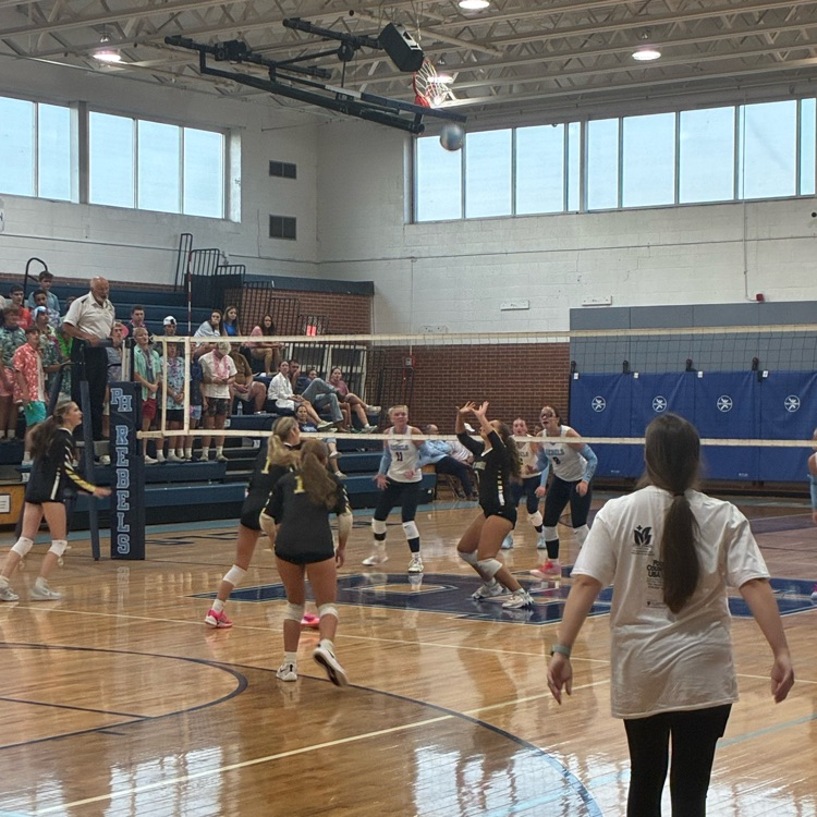 The setter receives the ball as the outside hitter lines up, and the coach waits for a possible spike!
