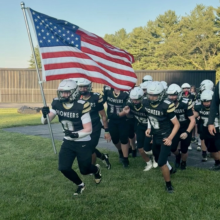 The football team runs out with the American flag.