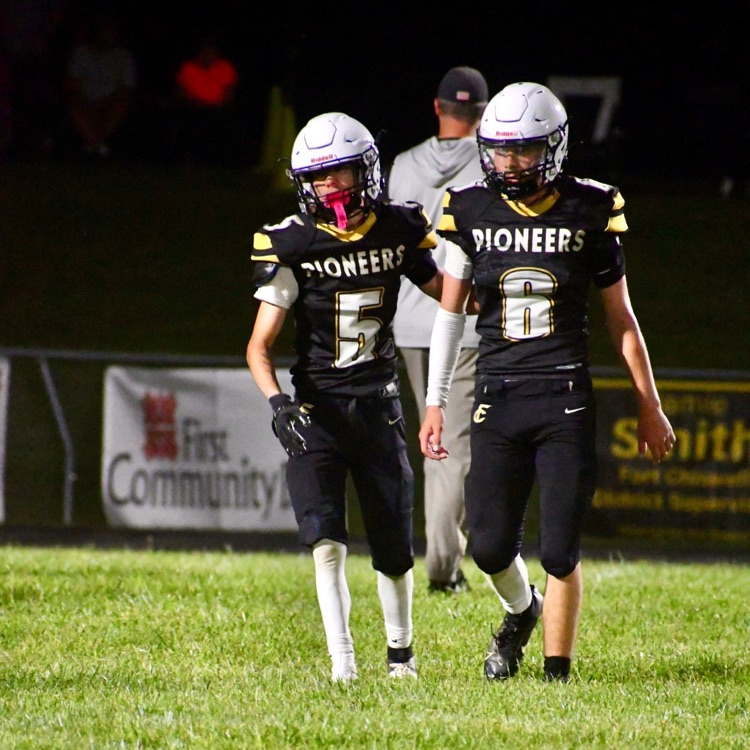 Football players #5 and #6 walk beside each other after a play.