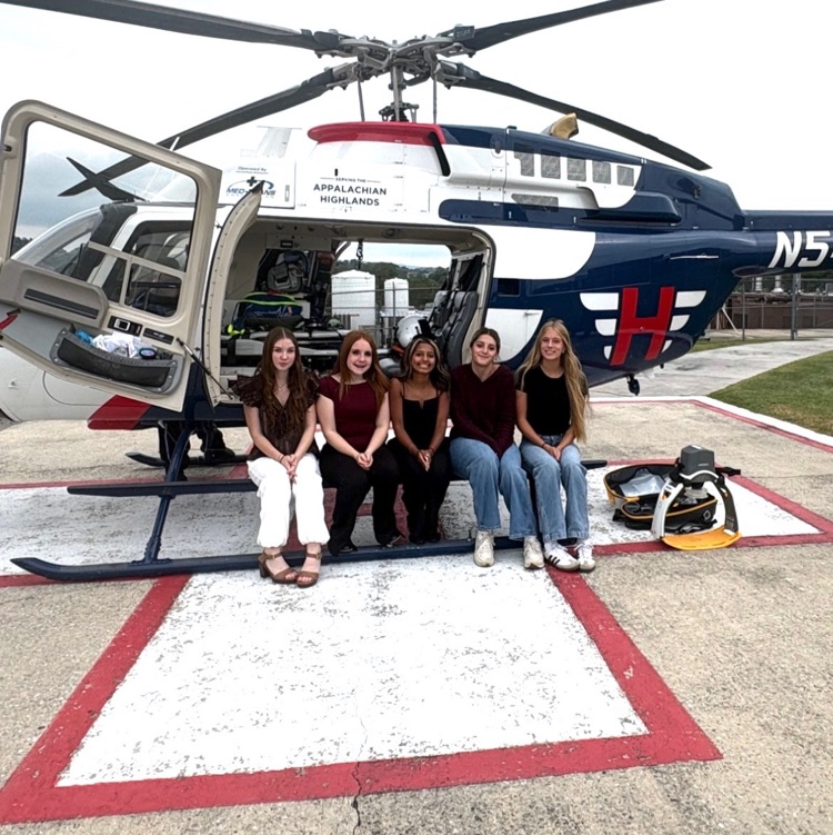 5 girls sitting at the foot of a helicopter