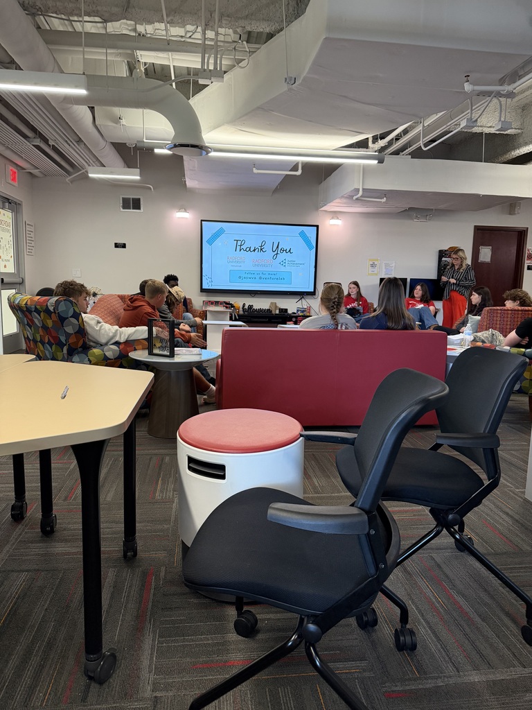 Students sit around in chairs as they hear a presentation.