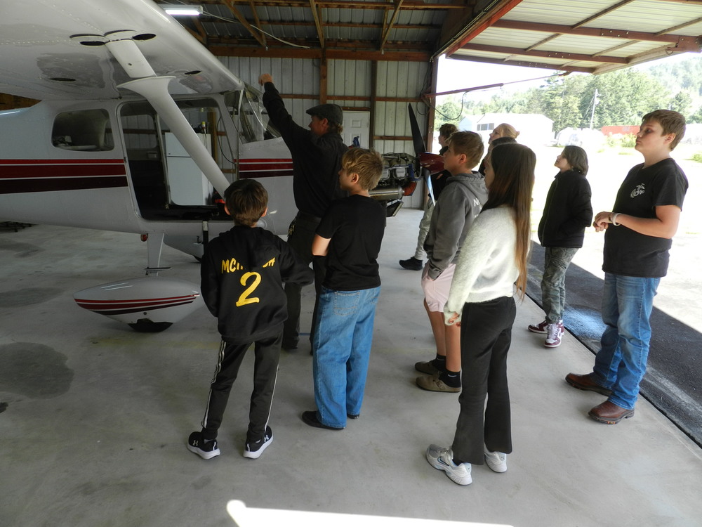 middle school students looking on as a man shows them the helicopter
