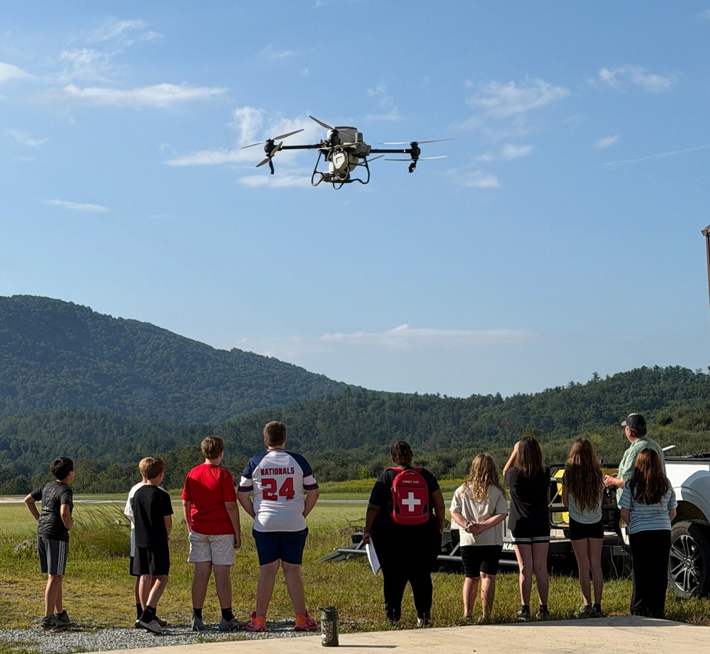 middle school students looking into the sky at a drone hovering above