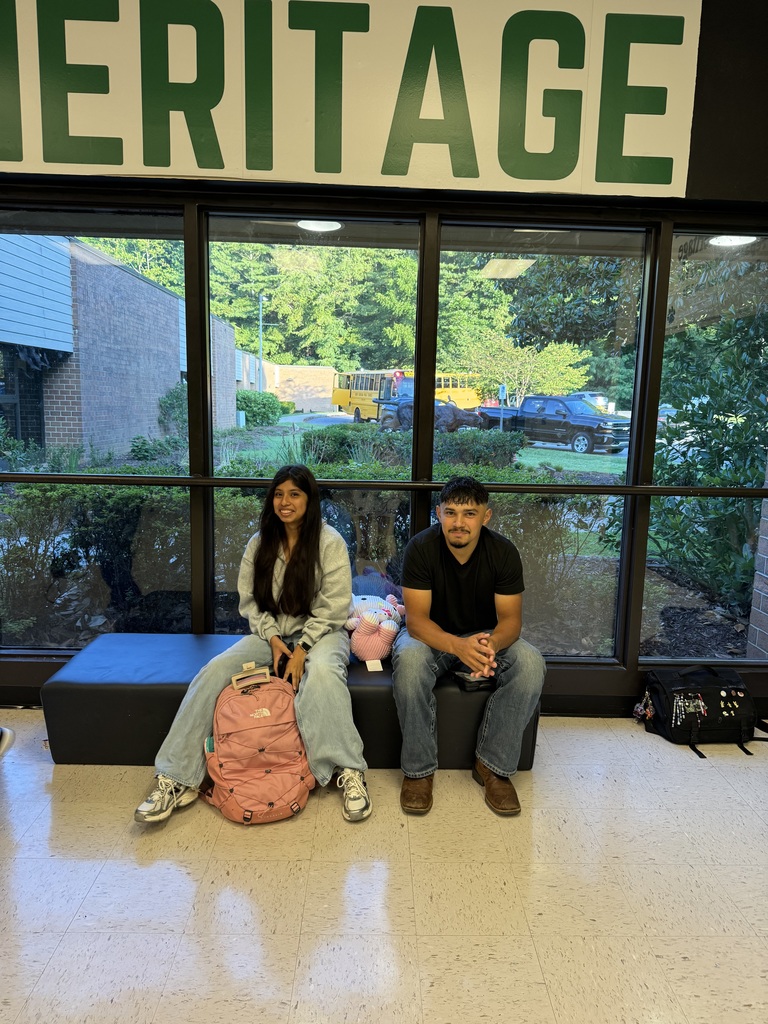 a teenage girl and boy sitting in front of a window, smiling