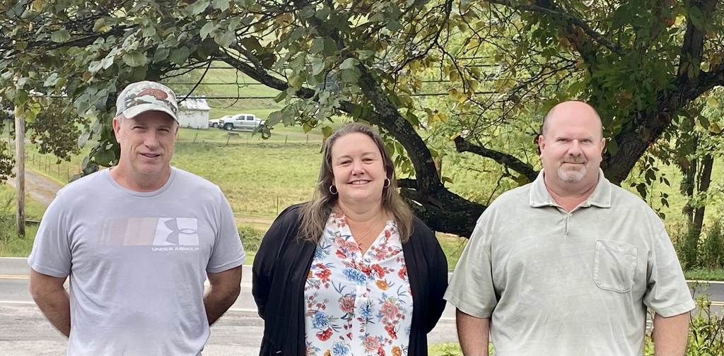 two men and one woman standing in a row smiling