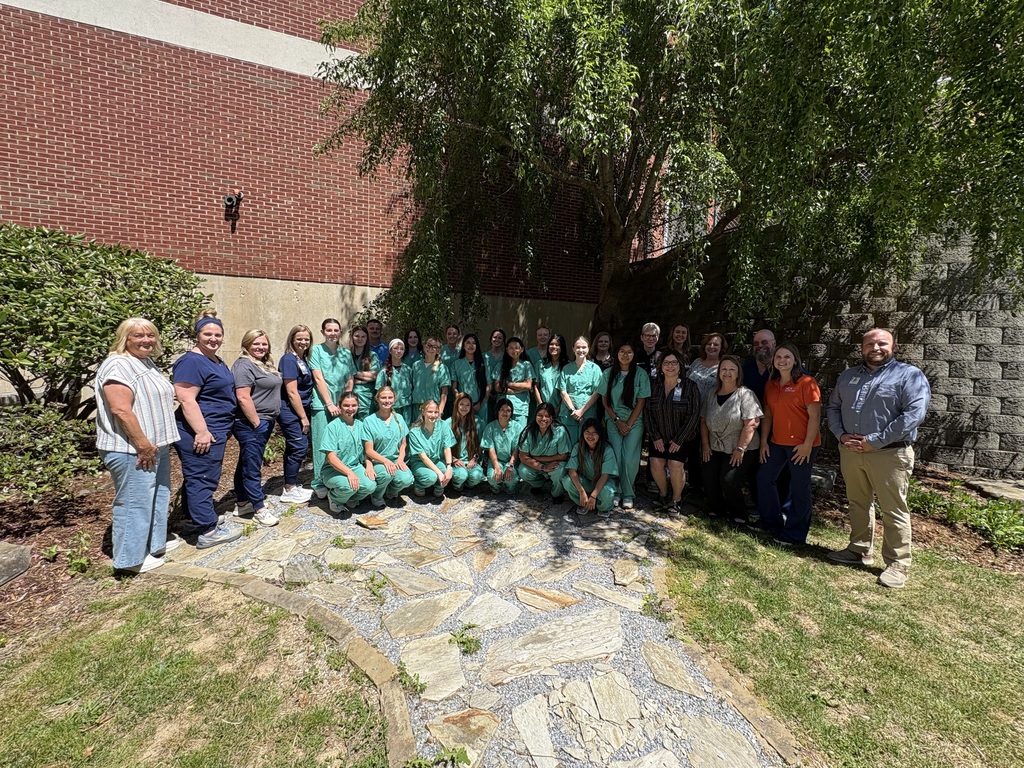 group of students in scrubs posing with instructors on each side of the students