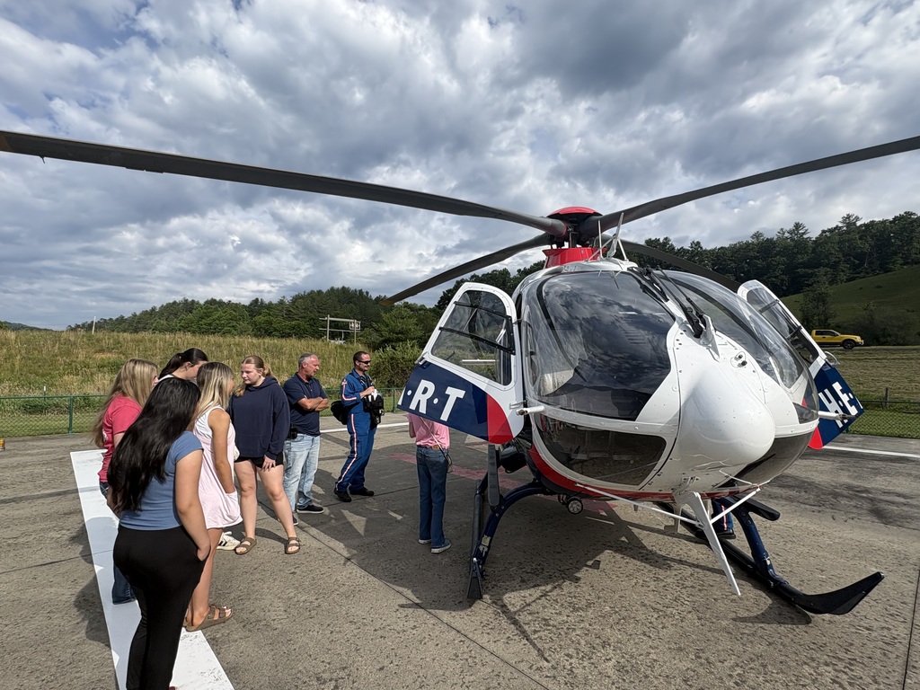 students standing beside a helicopter 