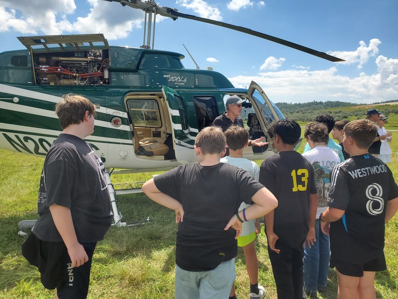 middle school students looking at a green helicopter