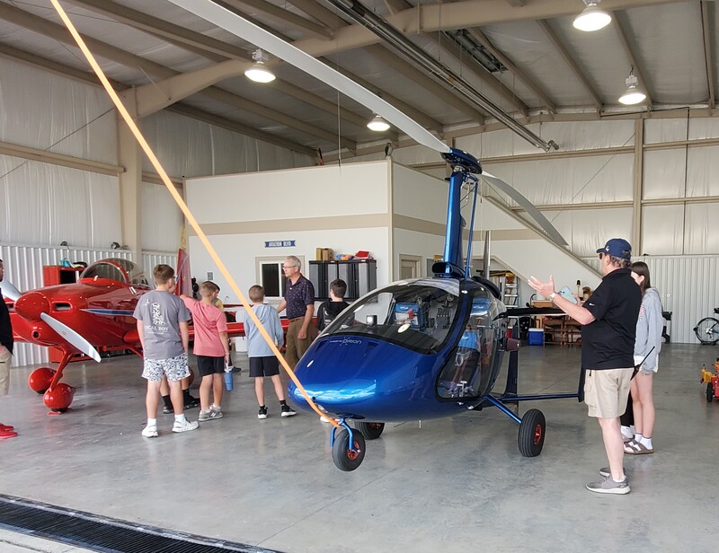 middle school students looking at a small blue gyro plane