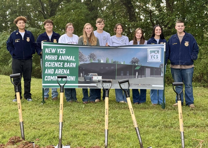 high school students lined up behind a sign for a new animal science barn and arena