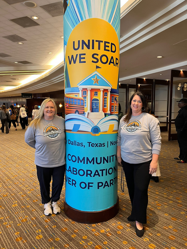 two women posing nex to a column that says "united we soar"