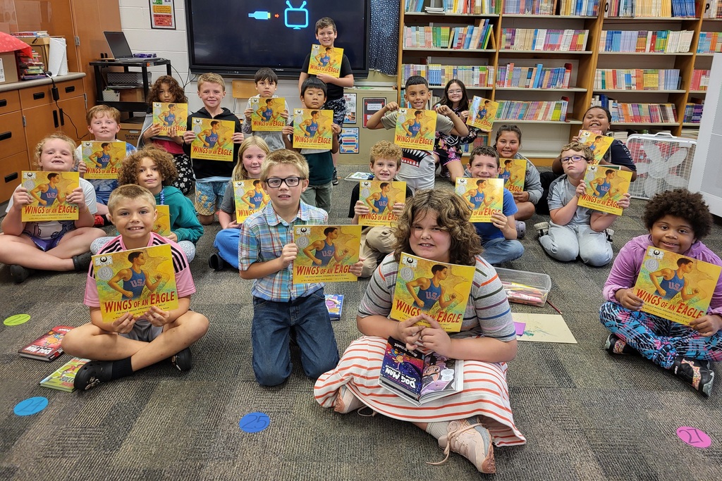 class of students holding books seated in the library