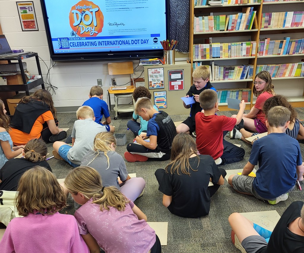 seated 4th graders drawing on cardboard