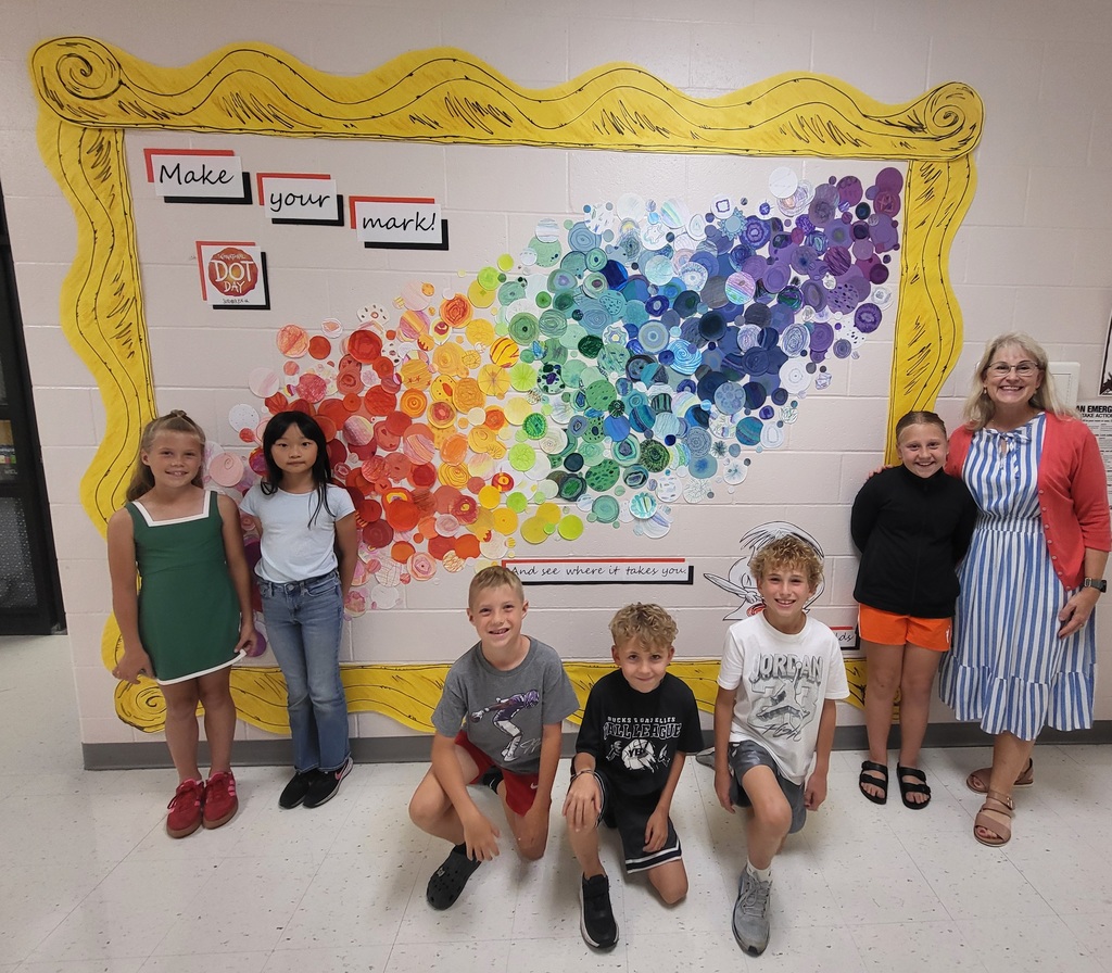 6 students and 1 adult in front of dot artwork
