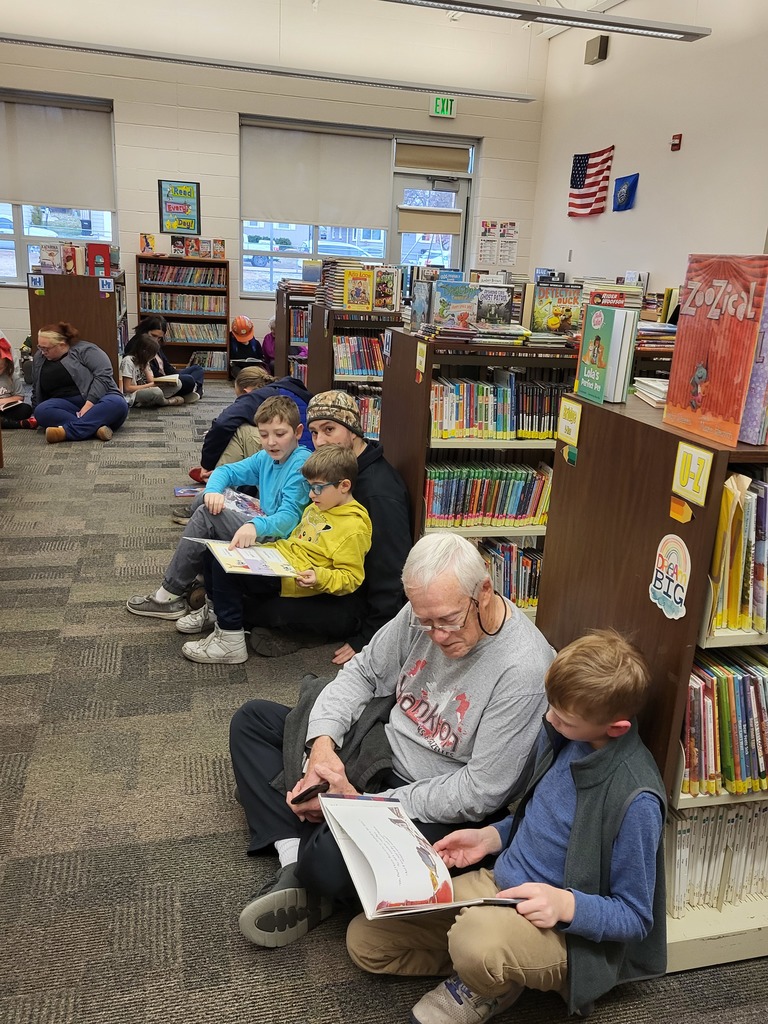 Families sitting by bookshelves reading books