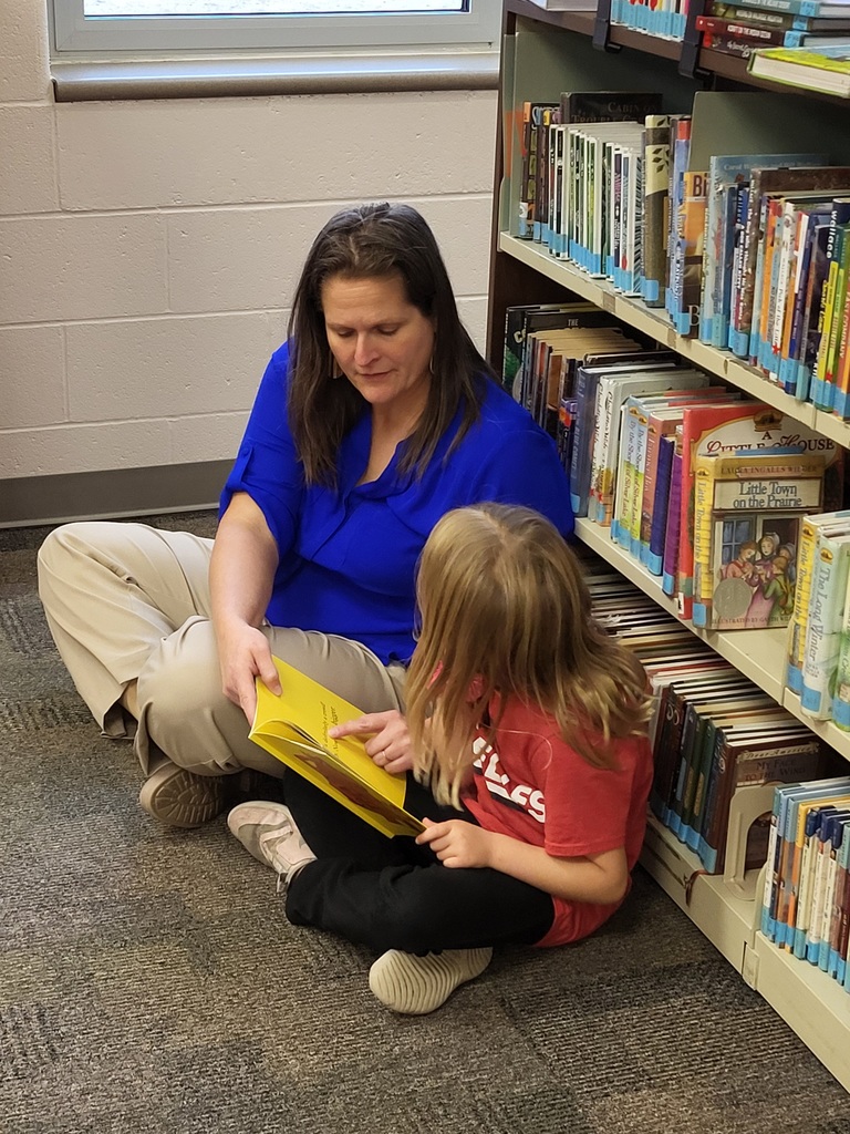 Woman and child sitting by bookshelf reading