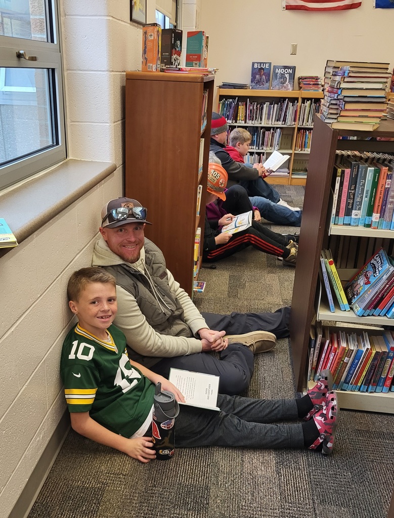 boy and father sitting on floor with a book