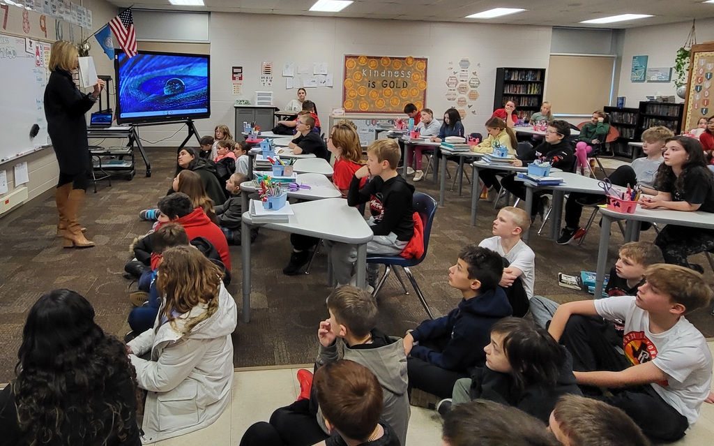 Woman reading to class of students at tables