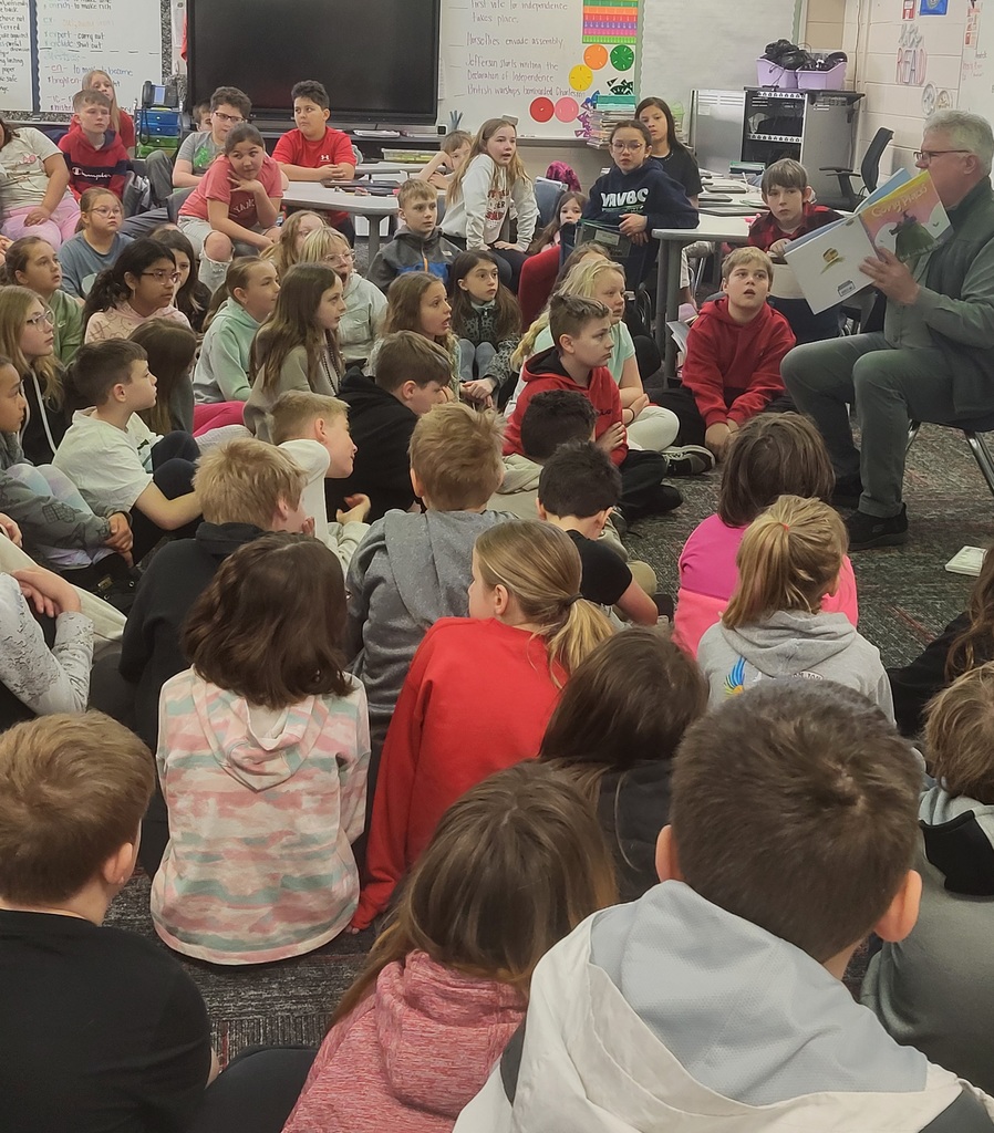 Seated man reading to group of students