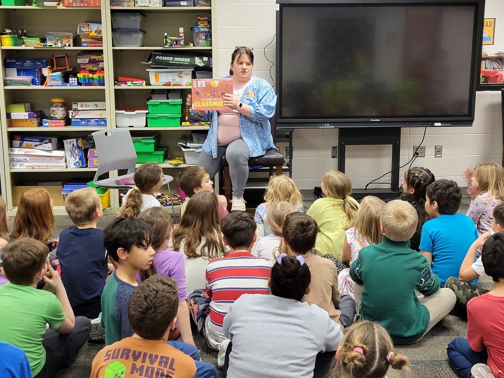 Woman seated to read in front of students