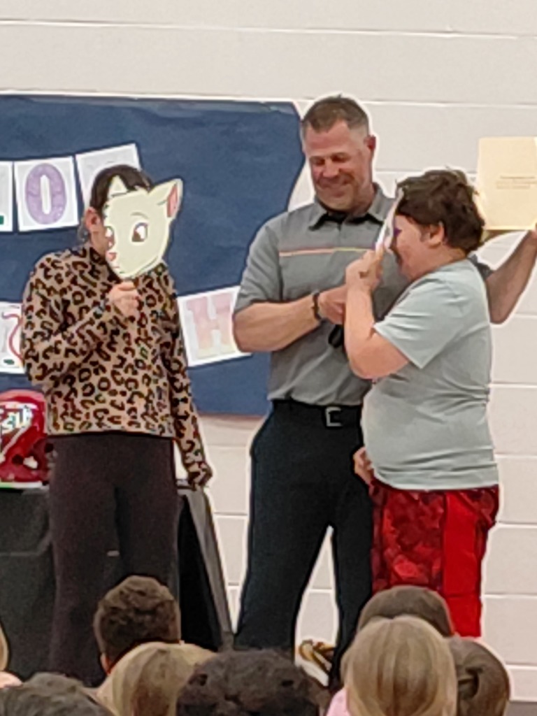 2 students with masks and man holding microphone