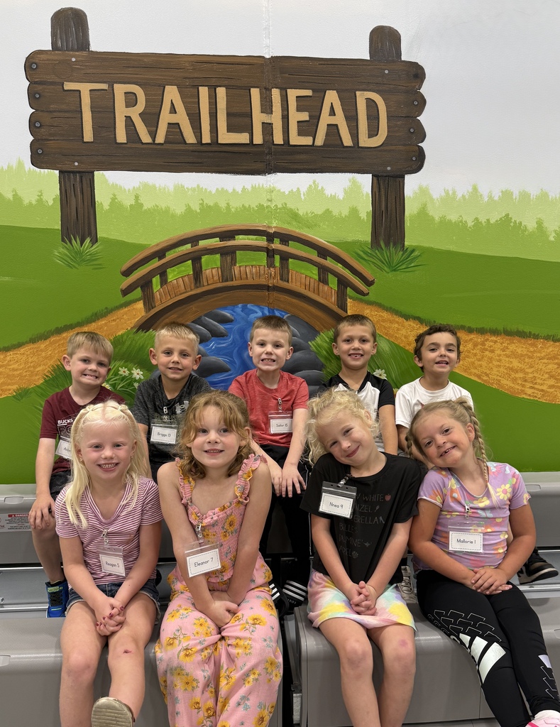 students smiling in front of Trailhead painting