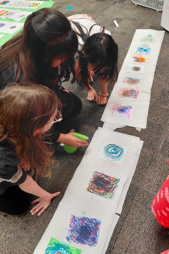3 students kneeling over art project