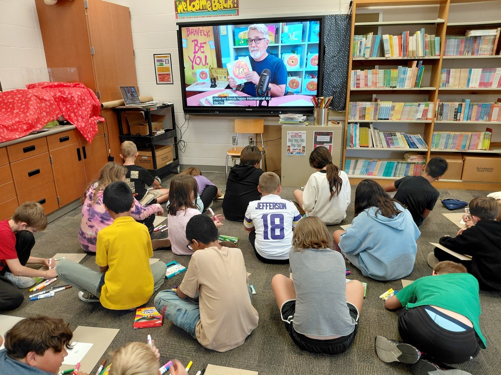 group of students seated on carpet watching screen