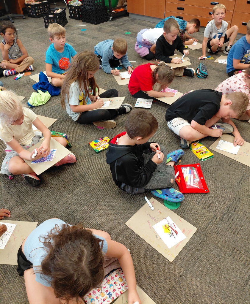 students drawing while seated on the floor