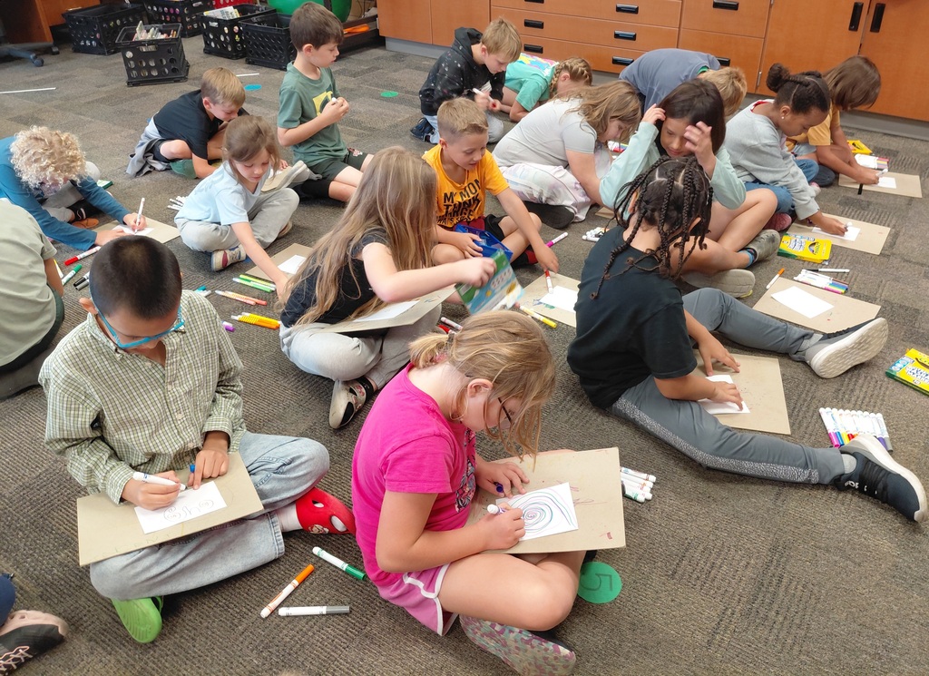 group of students drawing while seated on the floor
