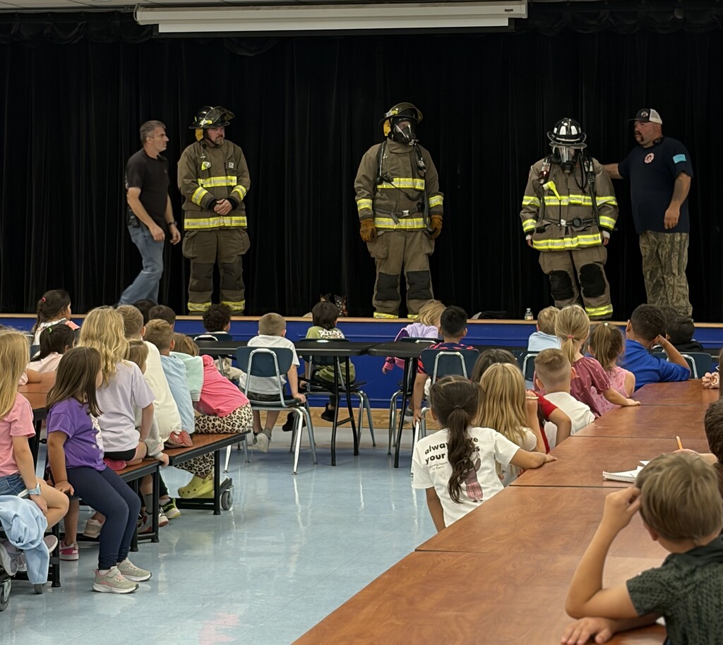 firemen  teaching a group of students about fire safety