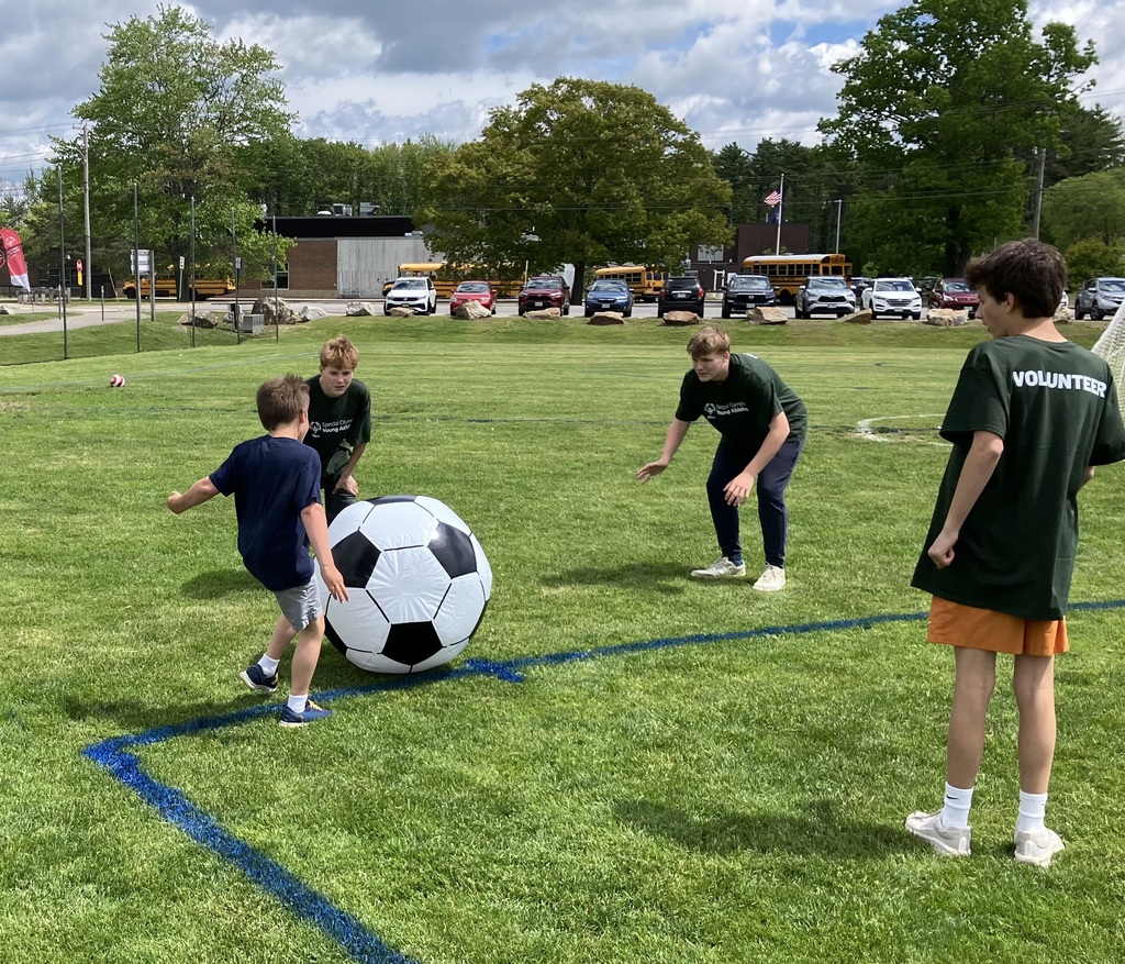 Young Athletes Festival - athlete kicks an inflatable ball to an 8th grader