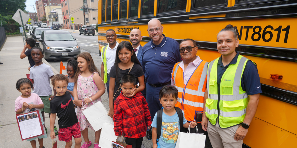 Young Children and school officials in front of yellow school bus