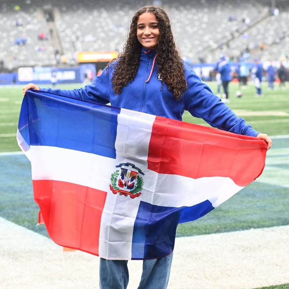 Myriam Areche holding Dominican flag on field at MetLife Stadium