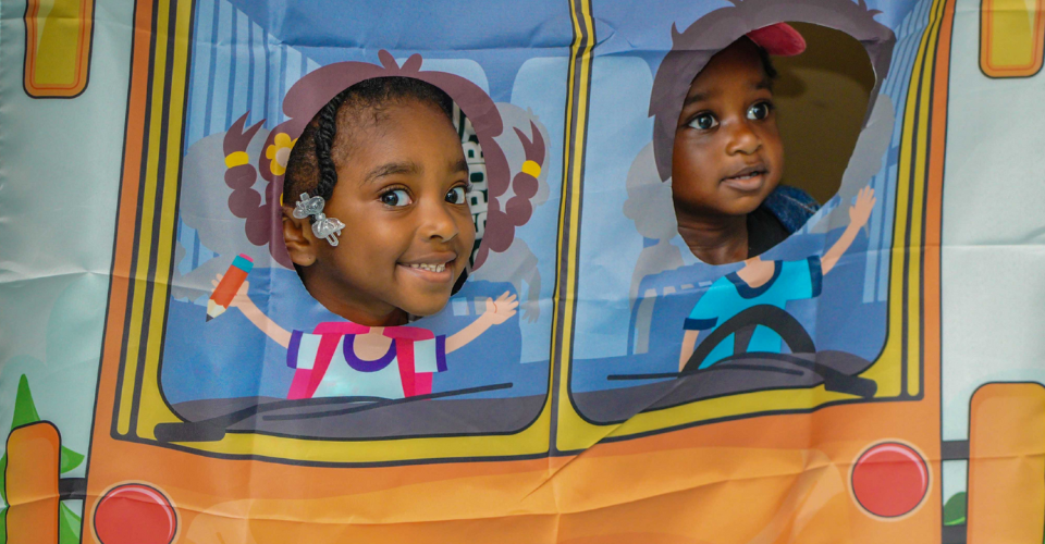 Young child looking out the window of the school bus on a rainy, late summer morning