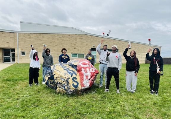 students standing alongside painted rock