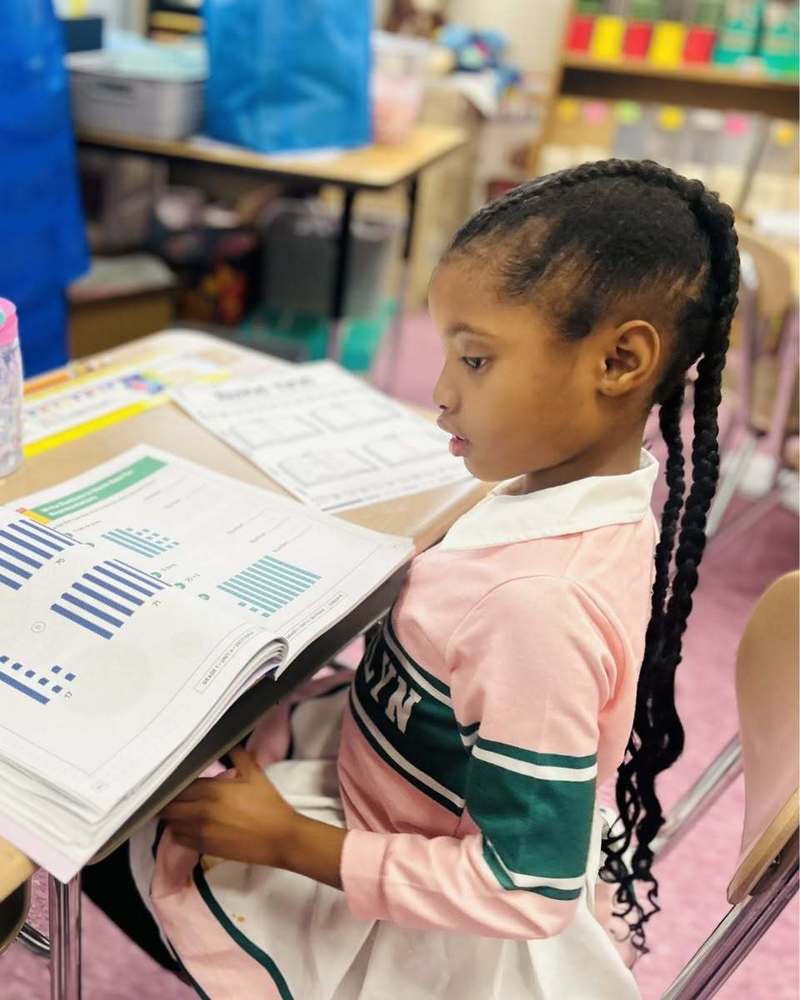 image of elementary age girl with texbook in classroom 