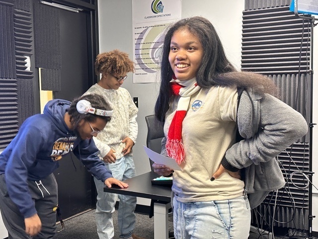 female and two male students in a podcast studio 