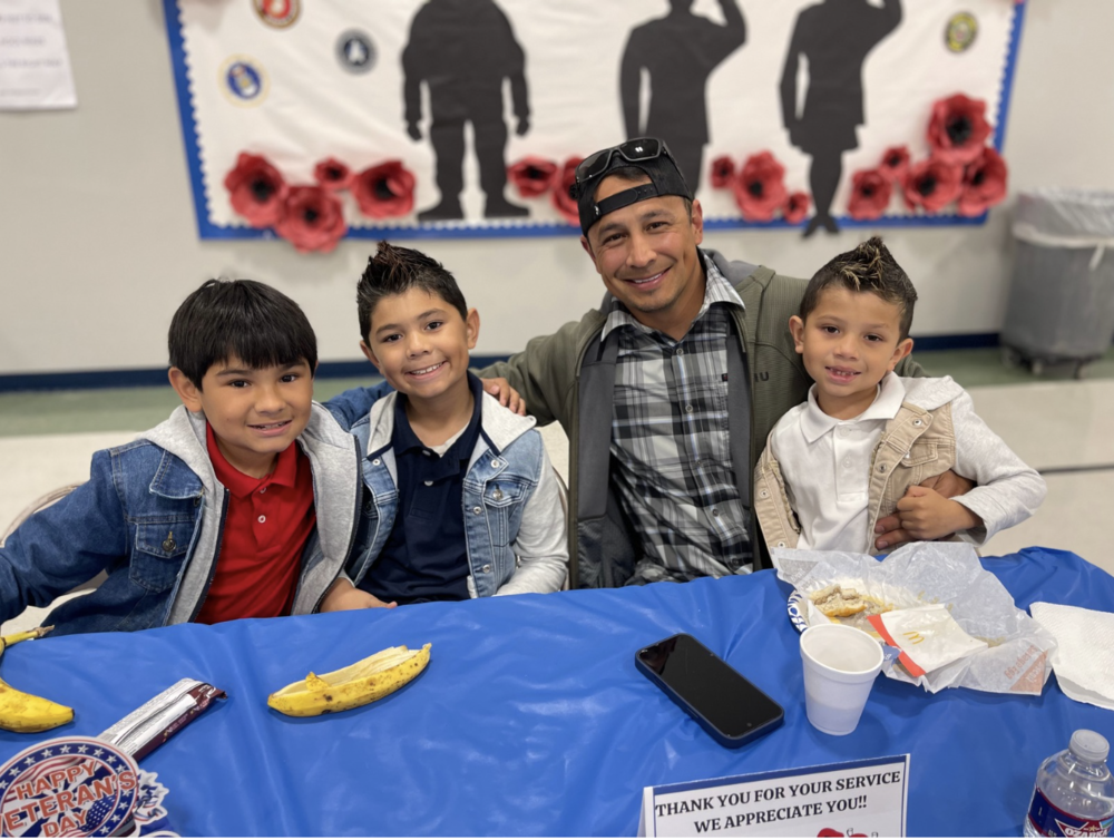 3 students posing with their veteran