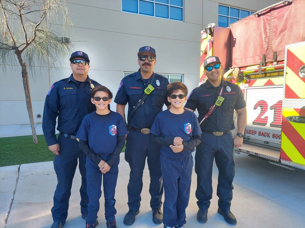 Students are posing in a picture with firemen.