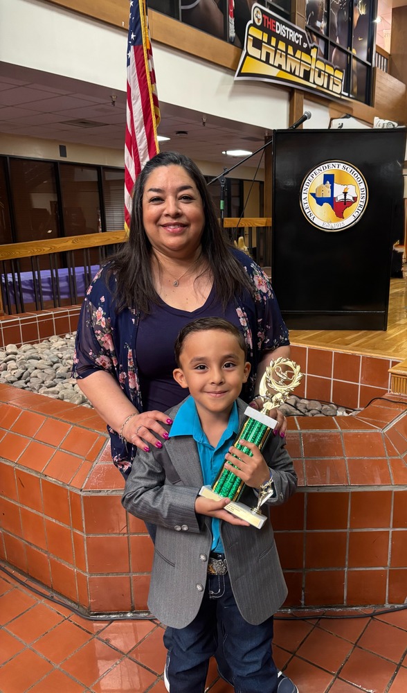 Student from kinder holding a trophy with a big smile after wining The Creafive Writing contest