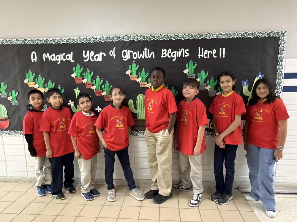 8 students posing with their prize shirts that say reading sparks magical growth