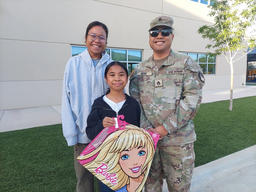 Female student taking a picture with her mom and dad, while holding a kite.