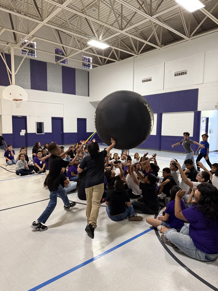 Students in gym playing with giant PE ball