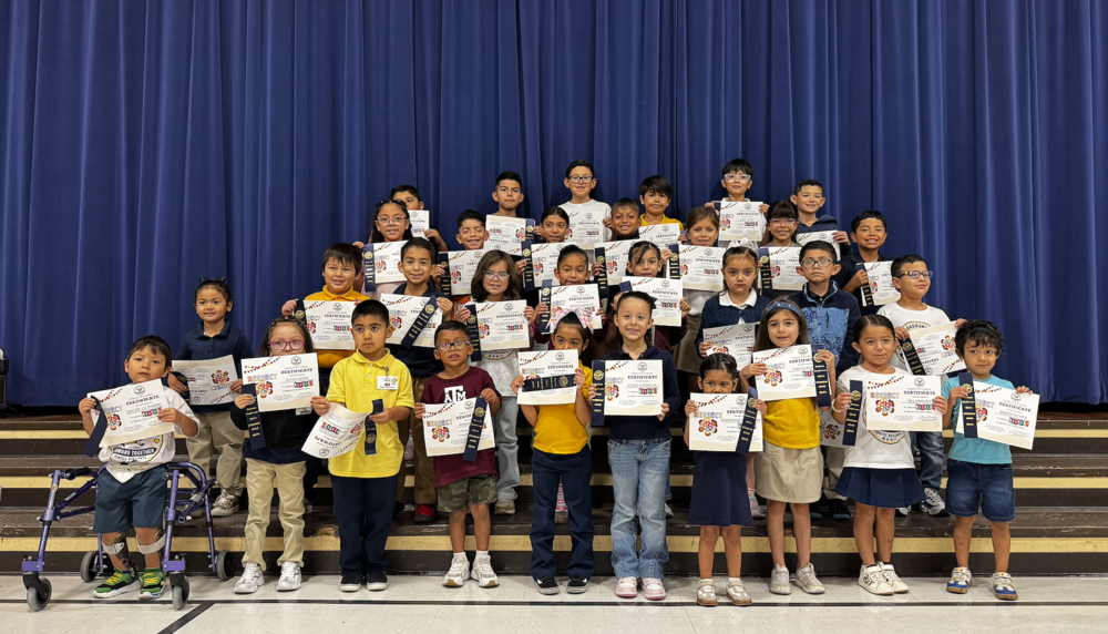 Group of students posing on stage steps with certificates and ribbons