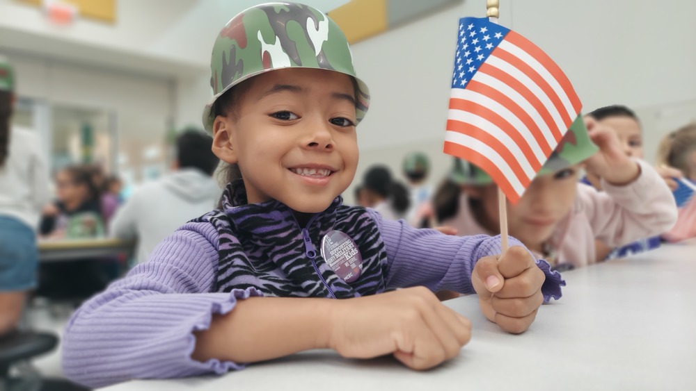Student poses for a picture while wearing purple to show support for the Month of the Military Child.