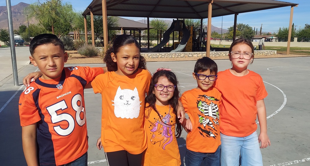 Male and Female students are lined up wearing orange hugging in unity against bullying.