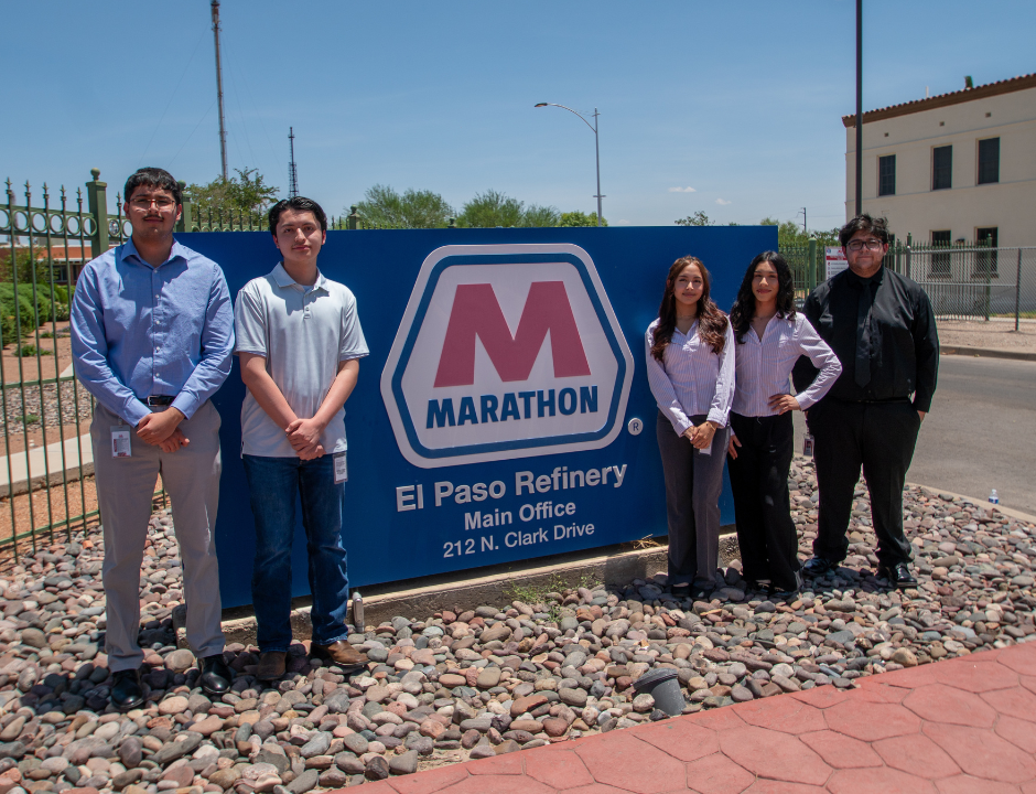 Five people stand in front of a large blue Marathon El Paso Refinery sign on a sunny day. They are dressed in business or business casual attire and are smiling at the camera.