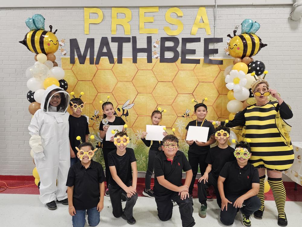 3rd grade Math Bee contestants and winners pose with the Counselor Camack in a Bee Hive suit and Principal Banegas in her Queen Bee Costume